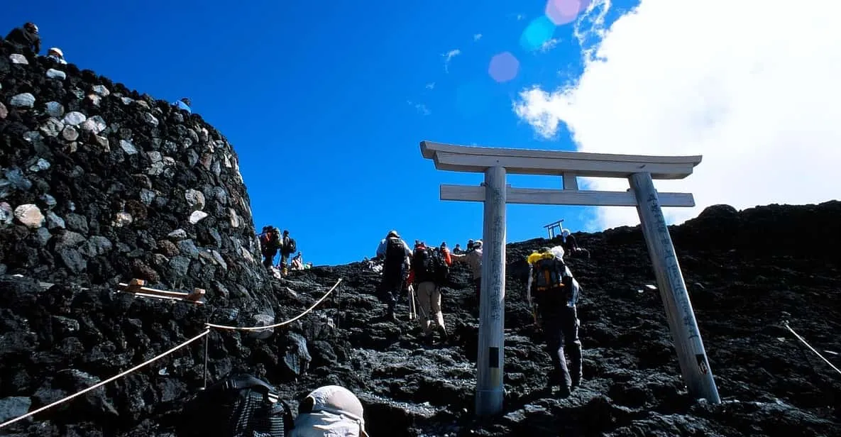 Climbers watching sunrise from the crater rim on a Mount Fuji climbing tour above the clouds in Japan
