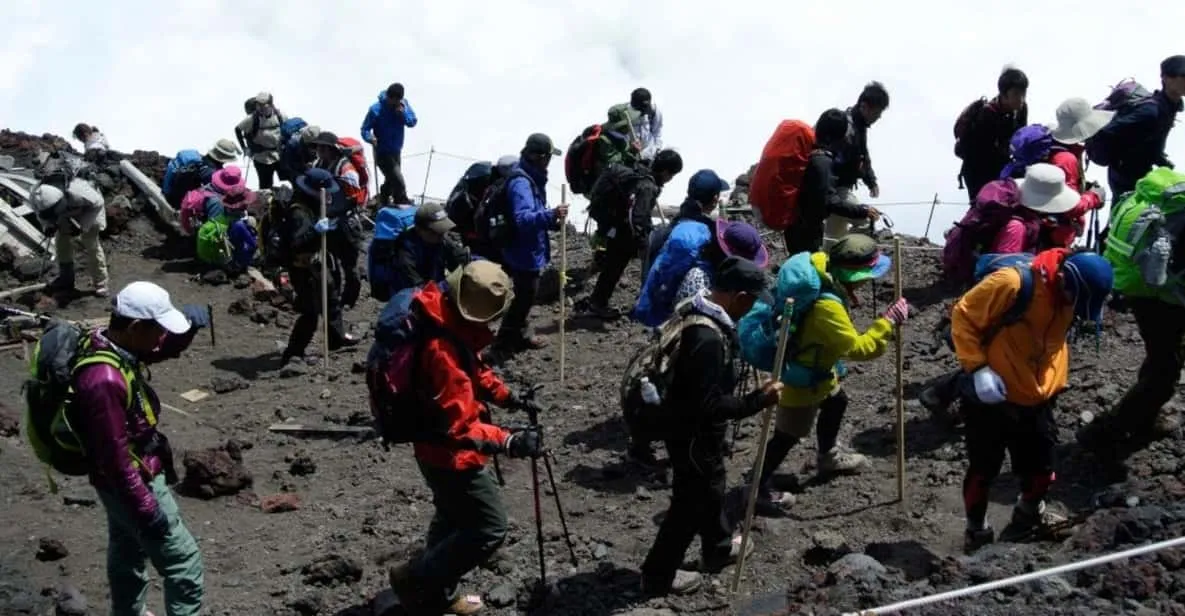 A guided group ascending the rocky Yoshida trail on a Mount Fuji climbing tour toward the summit in Japan