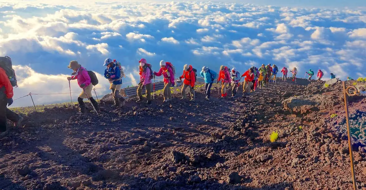 Climbers walking the rim of Hoei Crater on a quieter Mount Fuji climbing tour with the summit ahead in Japan